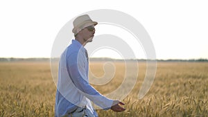 Man farmer in a hat walking in wheat field