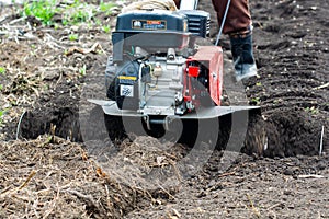 Man Farmer plows the land with a cultivator. Agricultural machinery: cultivator for tillage in the garden,motor