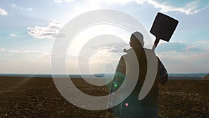 Man farmer silhouette red neck holding a shovel in his hand walking across the field a pile of dirt soil. Eco smart