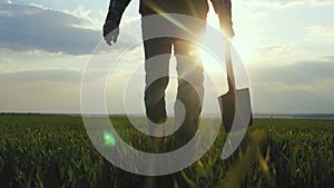 Man farmer a silhouette red neck holding shovel in his hand walking across green field a pile of dirt soil. Worker