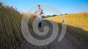 Man farmer walking down golden Barley field