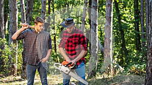 Man farmers relax in forest. rangers use lumberjack equipment. Lumberjack with saw and ax. Harvest firewood. hiking in