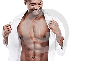 Man, fashion and muscle with abs, shirt and dressing for chest, african and male model in white background. Alone, smile