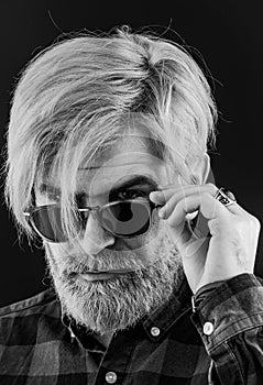 Man with fashion sunglasses. Head and shoulders portrait of a bearded middle-aged man looking at the camera over a grey