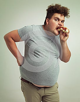 Man, fast food and eating hotdog for lunch in studio background for snack, hunger and craving for plus size guy. Male