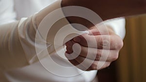 Man fastening buttons on his shirt sleeve. Wedding detail