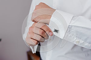 Man fastening a cuff-link on the shirt. Groom fastens cufflinks on the shirt