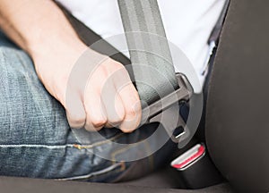 Man fastening seat belt in car