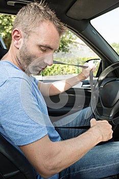 man fastening seatbelt in car