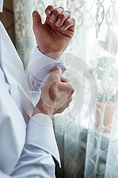 A man fastens a cufflink on his shirt. Groom fastening cufflinks on his shirt