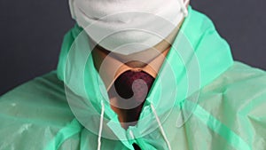 A man fastens a protective coat with buttons. He puts a hood on his head. Close-up shot. Virus protection