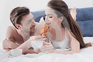 Man feeding his girlfriend in bed