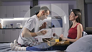 Man feeding his girlfriend with breakfast in bed