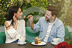 Man Feeding His Girlfriend Tasting Cake Sitting In Cafe