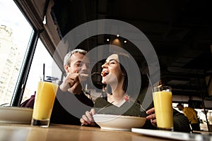 Man feeding his girlfriend a tomato. WAttractive woman smiling and dreamly smiling. She is happy that she will get more