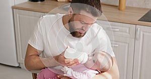 Man feeding newborn with formula in a bottle