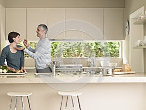 Man Feeding Wife At Kitchen Counter