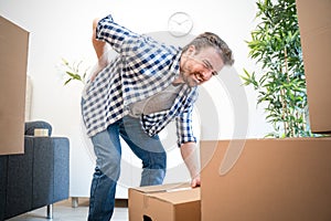 Man feeling back ache cramp lifting heavy boxes