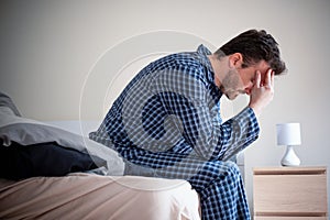 Man feeling bad and seated on the bed