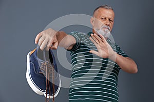 Man feeling bad smell from shoes on color background