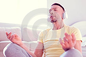 Man feeling calm and relieved while meditating and concentrating on calm music