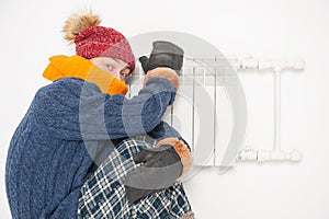 Man feeling cold in hat and pullover sitting close to radiator. Gas crisis concept