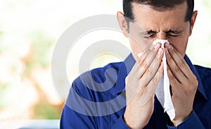 Man feeling ill and blowing his nose with a tissue