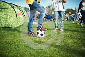 Man, feet and playing with soccer ball outside of his tent group of colourful camping. Row of marquees placed on ground