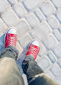 Man feet in red sneakers on cobbled road