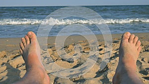 Man feet sunbathing on the beach against the background of sand and blue sea with waves, Man bare feet on a beach