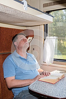 A man fell asleep while reading book in his compartment