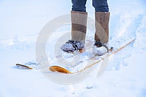 A man in felt boots on homemade skis walks through the snow into forest. Hiking, traveling, hunting, fishing.