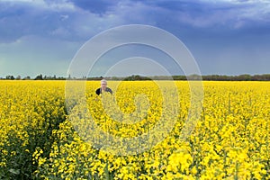 Man in the field of yellow canola against the blue sky