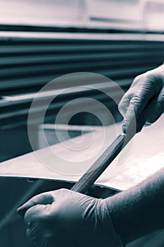 Man filing deburring a metal panel with a file.