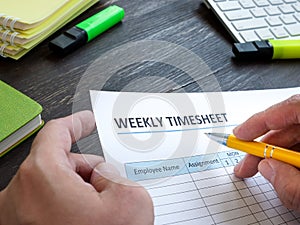 Man filing in weekly timesheet for employee in an office.