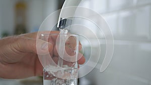 Man Fill Up a Glass With Fresh Water From Kitchen Faucet photo