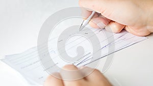 Man filling banking cheques for monthly payments and taxes photo