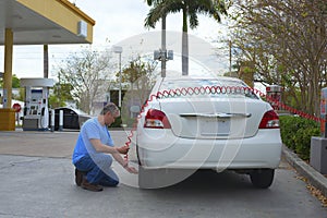 Man filling car tire with air at a gas station with a coin operated compressor pump