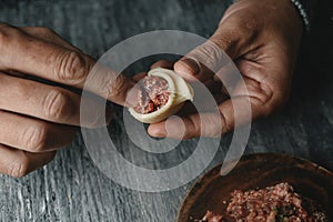 man filling a Catalan galet with raw ground meat photo