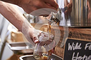 Man Filling Container With Wild Honey In Sustainable Plastic Free Grocery Store