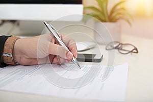 Man filling form with pen in lefty hand photo
