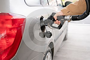 man filling fuel tank of his car with diesel fuel at the gas station close up, as cost of fuel going up