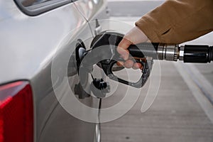 Man filling fuel tank of his car with diesel fuel at the gas station close up, as cost of fuel going up