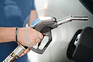 Man filling gasoline fuel in car. Hand refuelling the car, pumping gasoline in automobile at petrol station. Close-up of male hand