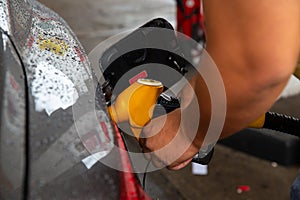 Man filling gasoline fuel in car holding pump.
