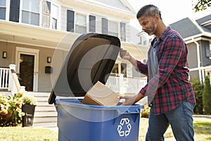 Man Filling Recycling Bin On Suburban Street