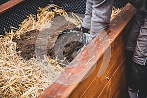 Man filling straw and soil into the raised bed