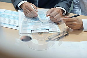 Man filling in U.S. Individual income tax return, tax 1040 at table.