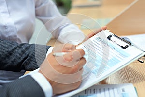 Man filling in U.S. Individual income tax return, tax 1040 at table.