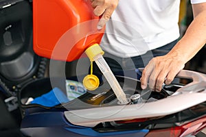 Man filling up fuel into Motorcycle tank with gasoline from spare tank. canister of 5 liters, maintenance, repair motorcycle conce